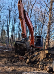 A huge tractor and loader was used to clear a path, so silt could be removed and placed outside the pond.