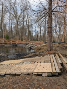 Wood and steel mats are placed on the path so the tractor can work as close to the pond as possible.