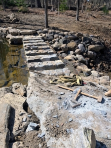 Concrete was also used to bond the rocks together. Here, one can see the spillway taking shape.