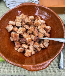 A bowl of homemade multi-grain croutons with walnuts are provided to top the salad or eat out of hand.