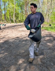 Ryan sprinkles fertilizer all around the planting area.