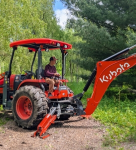 Chhiring uses the backhoe to help dig holes for the willows. This area is still in the beginning stages of development, so the ground is still un-groomed.