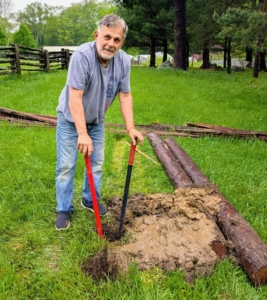 Fernando begins the job of digging post holes using a post hole digger, a hand tool used to manually dig deep and narrow holes in order to install fence posts.