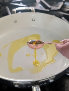 Enma heats one tablespoon oil in a medium skillet over medium-high heat until it is shimmering. She is using a Martha Stewart nonstick pan.