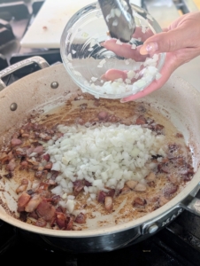 She adds the chopped onions and garlic plus a pinch of salt.