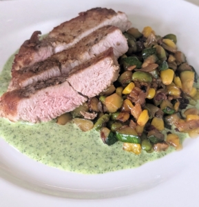 The pork is sliced and served alongside the succotash and basil aioli.
