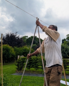 Using a line of twine secured above from one end to the other, Pete ensures the stakes are all centered perfectly.