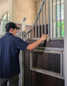 Another regular stable chore involves keeping the building's interior clean. Here, Juan wipes down the stable bars and doors.