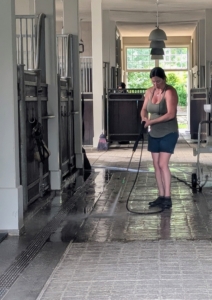 Later in the day, Helen, power washes the stable floor in preparation for a photo shoot. It's also important to keep various areas clean and tidy for production use.