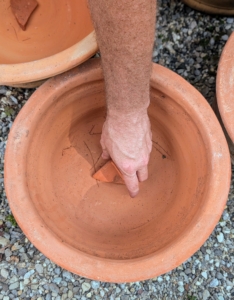 Ryan places a shard on top of the pot’s hole to maintain good drainage and to prevent soil from escaping.