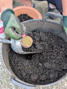 Ryan adds a couple scoops of fertilizer and mixes it thoroughly with the Miracle-Gro potting soil.