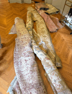Also for sale - a beautiful collection of rolled vintage and antique-style rugs, showcasing a variety of muted, time-worn palettes from soft blush and sage to cream, gold, and burgundy.