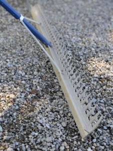 Meanwhile, Pete uses a landscape rake to spread and level the gravel. These rakes have one straight edge and one toothed edge.