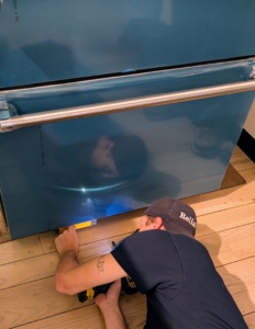 Before rolling it completely into place, check the refrigerator for adjustable feet. Most modern units, like this Viking, will be equipped with leveling systems that can be raised or lowered to ensure stability and good fit.