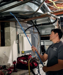 As the hoses are snaked through the air vents from above, Hermes holds the hose from the basement to control its movement and airflow pressure.