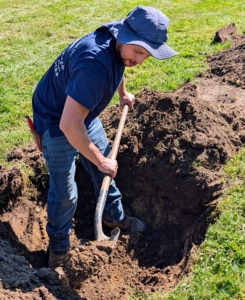 Alex manually helps to dig the holes to the appropriate depth.