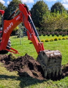 Next, Chhiring maneuvers my Kubota M62 tractor loader and backhoe to dig each of the holes.