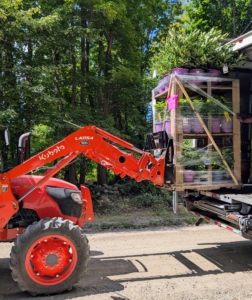 Here, the tractor is used to carefully transport pallets of plants from the truck to a designated area until they are planted in the ground.