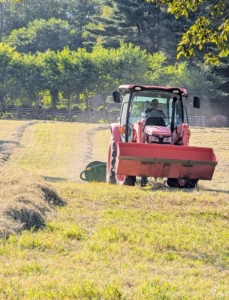 On this day, the tractor is used to pull a special agriculture attachment that rakes the cut and dried hay and forms it into windrows that can be baled.