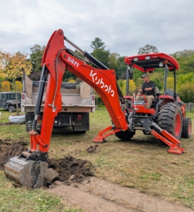 The Kubota M62 Tractor Loader Backhoe is essential for digging holes. It has a 63 horsepower engine and a powerful backhoe with 169.8 inch digging depth.