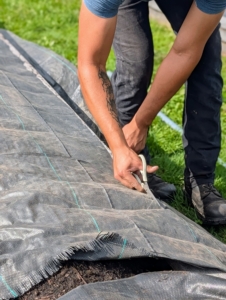 Matt covers the entire bed with weed fabric. I like to use a durable and thick fabric that can last through the winter. Here, Matthew cuts it to size.