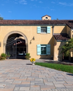 The Rosen House is a two story stucco building with a red tiled roof in a variety of asymmetrical gables and hip configurations.