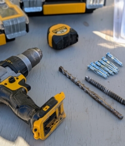 Pete gets all his supplies ready - concrete anchoring screws, a drill, the proper drill bits, and a measuring tape.