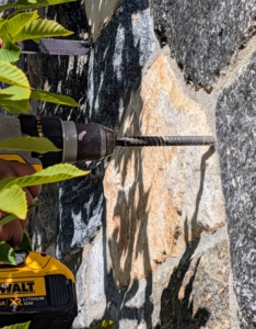 Next, using the drill, Pete makes a two inch deep hole in the wall at about the center point of trellis level with one of the cross pieces.