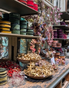 These tables and shelves are filled with ribbons, ornaments, and lights.