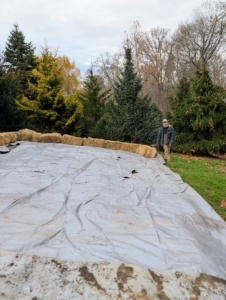 Chhiring counts how many bales are still needed. It's important to weigh it down all around the bed, so wind cannot blow the tarp off the tubers.