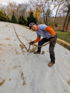 And finally, aside from the hay to help keep the tarps in place, Pasang uses old, heavy chains on top of the bed. Here he is placing one across the center.