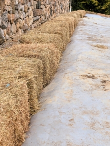 Here, one can see how the tarp is placed under the bales and weighted down by the hay.