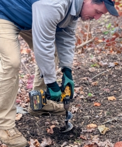 Ryan uses the auger attachment to make holes. The ground is a bit hard from the recent cold, but it’s still workable.