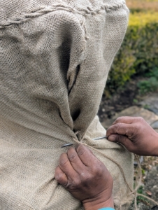Then Pete pulls it taut at the opening and sews it closed. If needed, Pete starts with small stitches and knots at the top and the bottom just to keep the fabric in place.