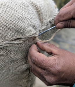 Then he sews the burlap along the open edge at the top.