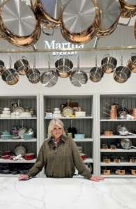 In my store, there are so many items for the home. Here I am under a rack of my signature pots. Every store has decorative touches from my own home. My most used pots and pans are hung above my personal kitchen counter for easy access whenever I am cooking.