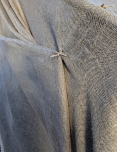 At the row ends, the burlap is pulled snug and jute twine knots are positioned to keep it closed.