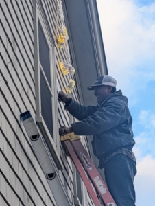 Here's Pete placing one on my Winter House. The shooting stars are hung securely using small nails and screw eyes at various points.