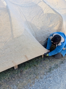Meanwhile, Adan holds the fabric taut over the framing and wooden stakes at the bottom.