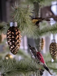 The trees shimmer with gold and green pinecone ornaments. Look closely, there are also birds sitting on the branches.
