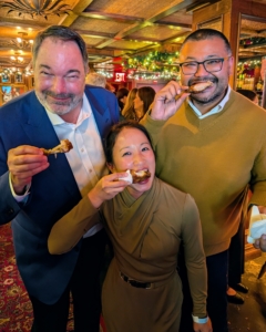 A fun photo of Marquee Brands Chief Financial Officer John Hayes, Ryan, and SVP Finance Ellen Yip, enjoying Buffalo wings fresh out of the oven.