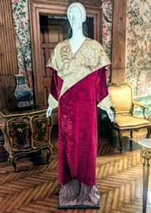 This wine-colored evening coat features a wide-collar with a pomegranate pattern stamped in gold, a signature pattern of Fortuny.