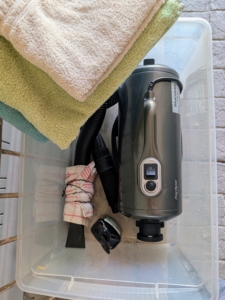 Carlos gathers everything he needs first, so there is no scrambling during the process. Here he has shampoo, the pet dryer, and a stack of towels.