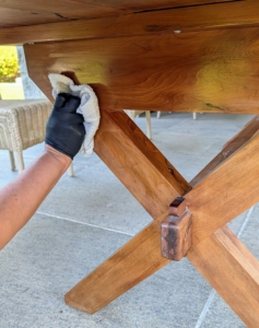 Next, she slowly wipes down the table, applying the oil on every surface of the legs and base.