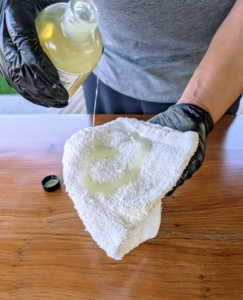 Elvira pours some Teak Tonic onto a dry cloth.