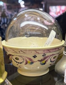 The bowl is Lusterware, or Lustreware. This is a type of pottery or porcelain that features a metallic glaze, giving the effect of iridescence. The ball inside is a hollow glass float, which was used to keep fishing nets afloat.