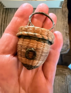 This is a miniature acorn shaped basket. Larger ones were used for tatting, or making lace. The basket would store the thread and the ring would be secured to a finger or wrist to keep hands more free for crafting.
