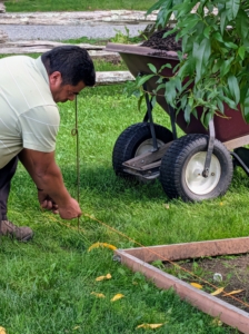 Arnold sets up the twine. I encourage my crew to use twine to line the spaces whenever they do this kind of work. Arnold secures the twine at one end of each row. This takes time to do, but this is a very important step in the process – it will guide all the work that is done.