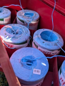 Large rolls of twine are positioned and tied to each other, so they can feed into the baler and secure the hay just before it shoots out into the wagon.