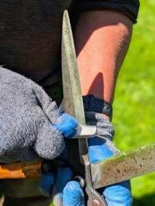 In order to do the jobs best, it is important to keep the shears as sharp as can be. Phurba carries a sharpener with him, so it's easy to maintain the blades while working. He holds the shear blade firmly and places an even and gentle pressure drawing the sharpener along the blade from hilt to tip.